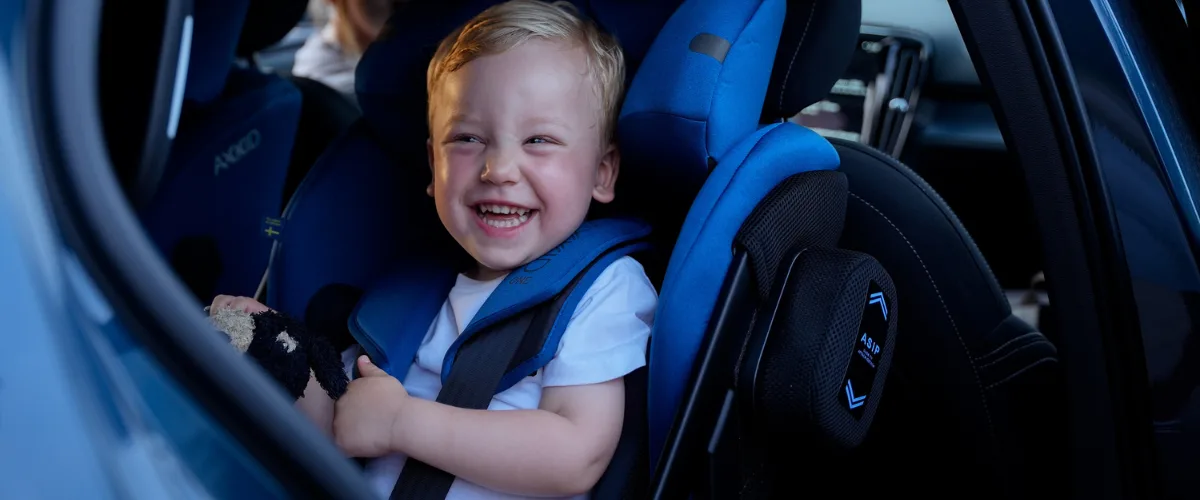 boy sitting in axkid bliue rear facing car seat
