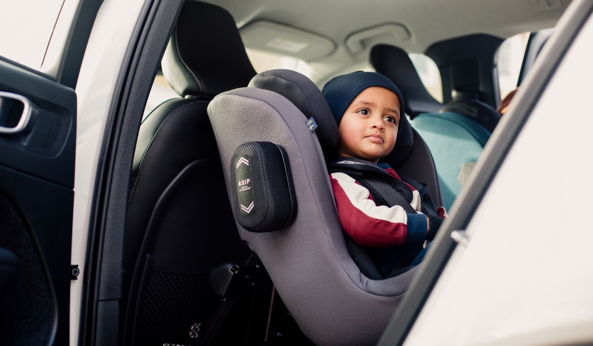 toddler sitting in a rear facing car seat with the car door open looking out through the opening