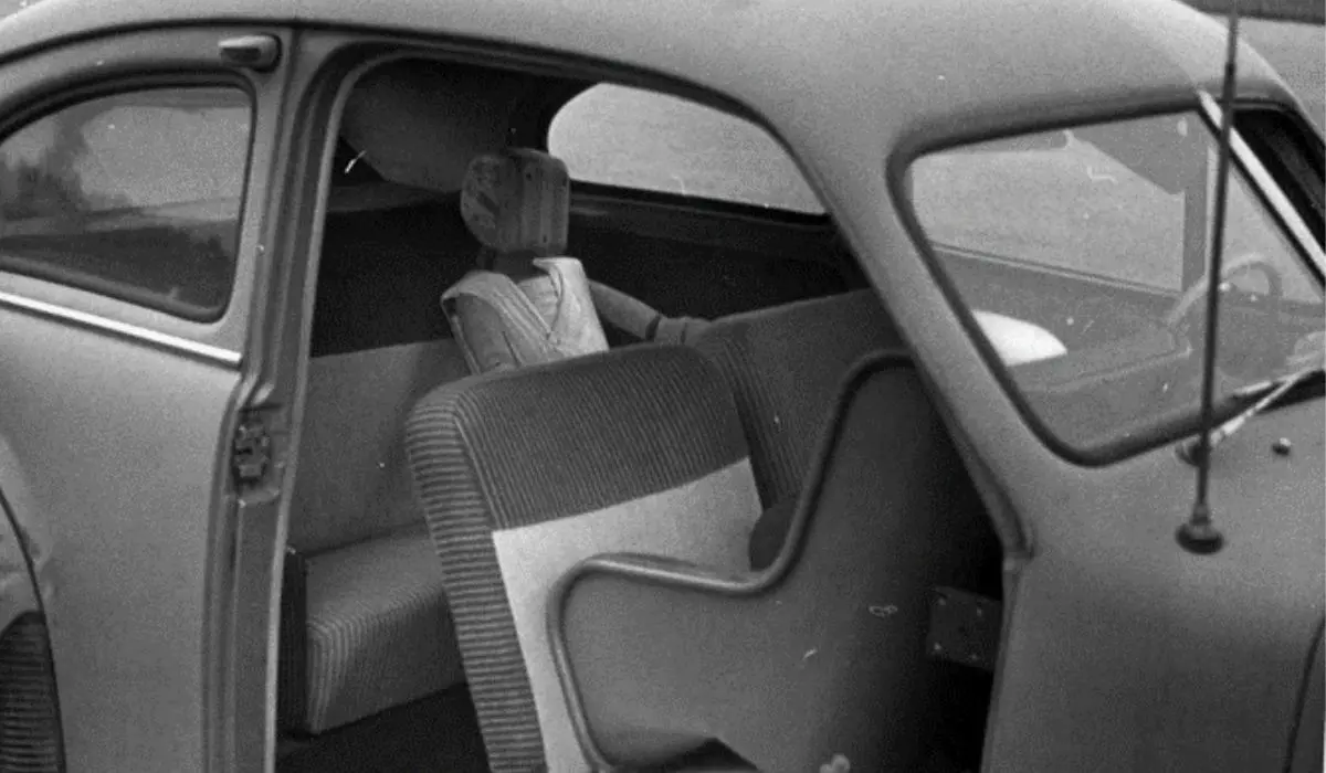old photo of a car with a wooden rear facing car seat in the front